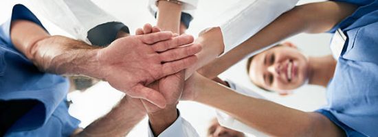 Shot of a diverse team of doctors joining their hands together in unity